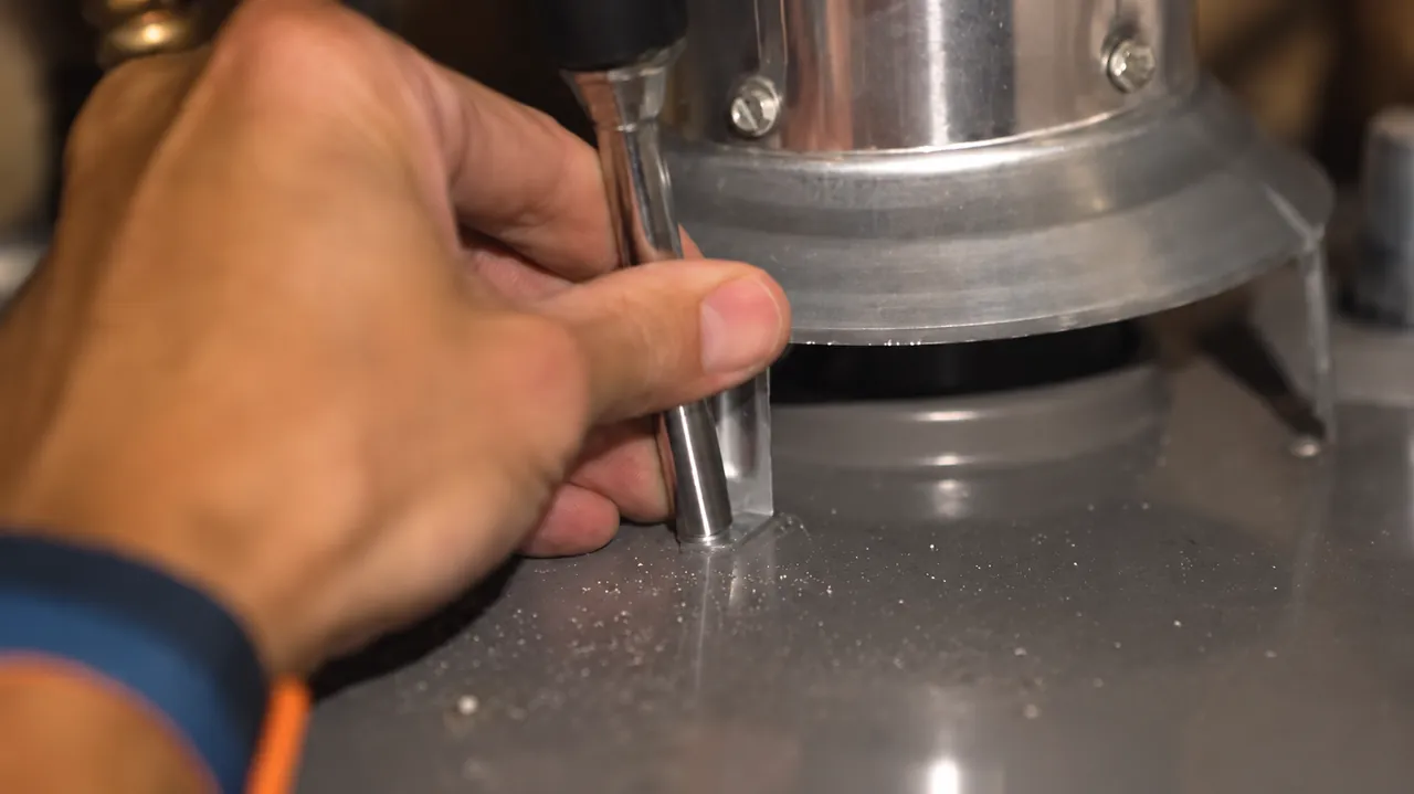 Hands checking a metal vent connection above a water heater